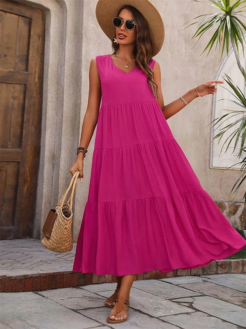 Woman wearing a pink dress and straw hat, standing outdoors.